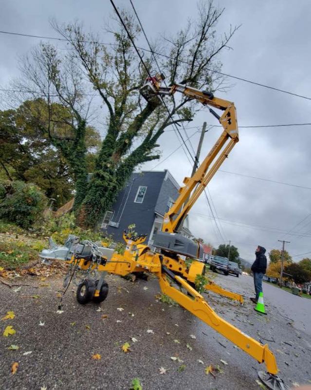 Tracked lift set up in the street with safety cones, working beside power lines